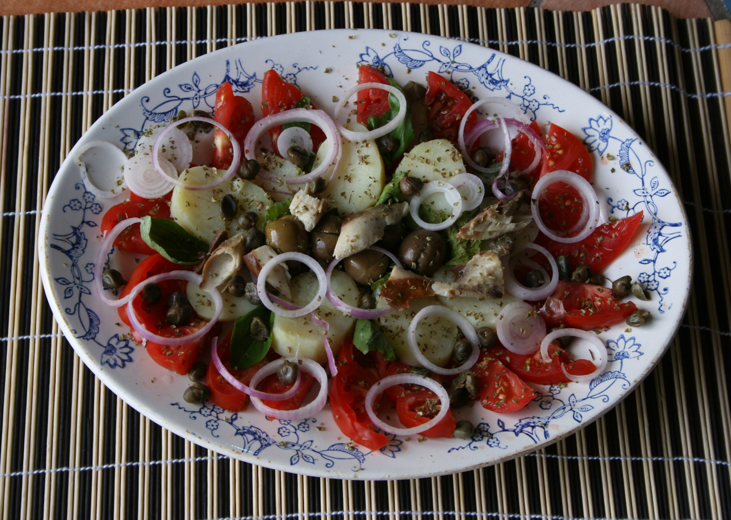 Nell’immagine si vede un’insalata di pomodori, capperi e cipolle.